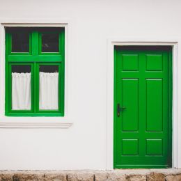 Elewacja budynku z zielonymi drzwiami i oknem w takim samym kolorze