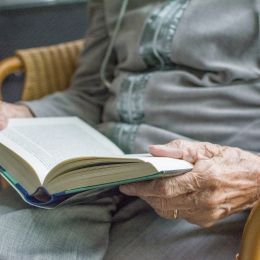 Dłonie starszej osoby trzymające rozłożoną książkę